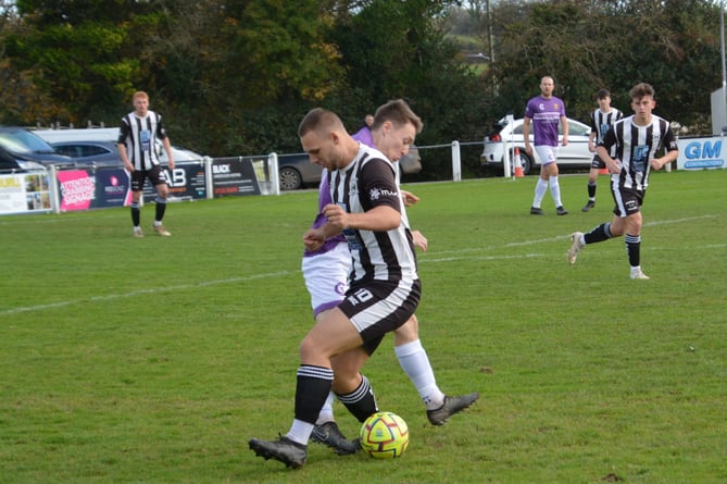 Holsworthy's Gavin Carter, pictured battling for the ball, had an eventful afternoon, scoring before being sent off for a two-footed lunge. Picture: Rodney Parrish