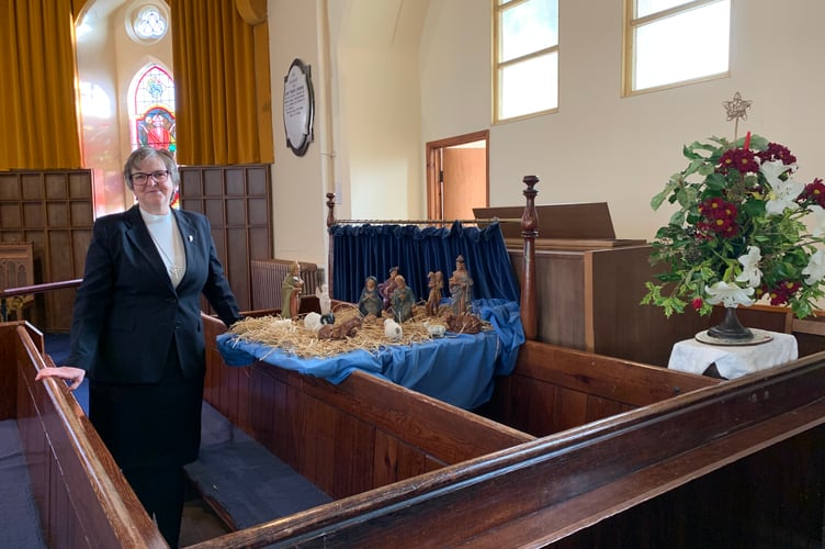 Deacon Ruth Richey beside Nativity scene in South Petherwin Methodist Church